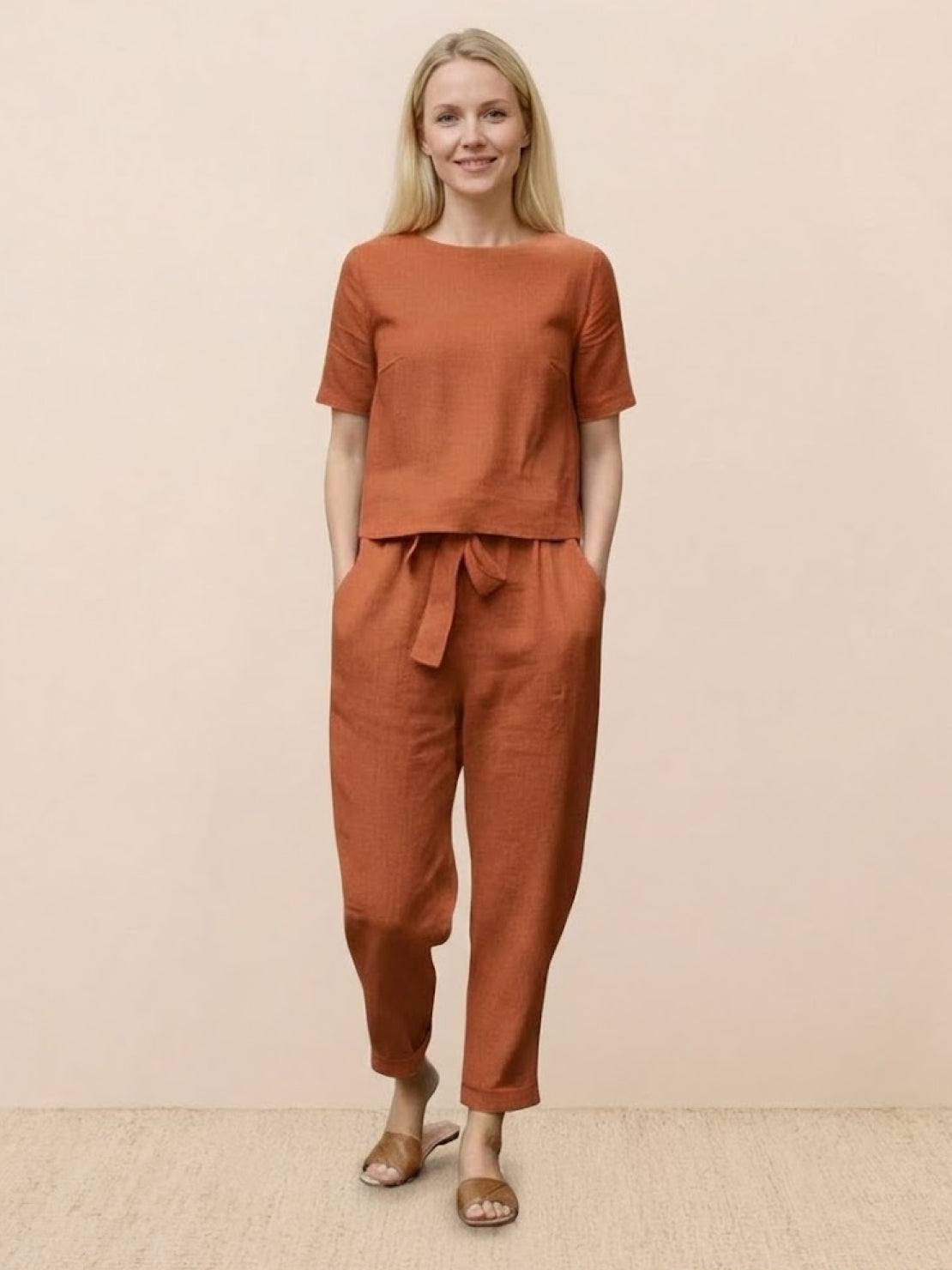 Woman wearing relaxed cotton linen set with monochrome top and straight-leg pants standing against white background