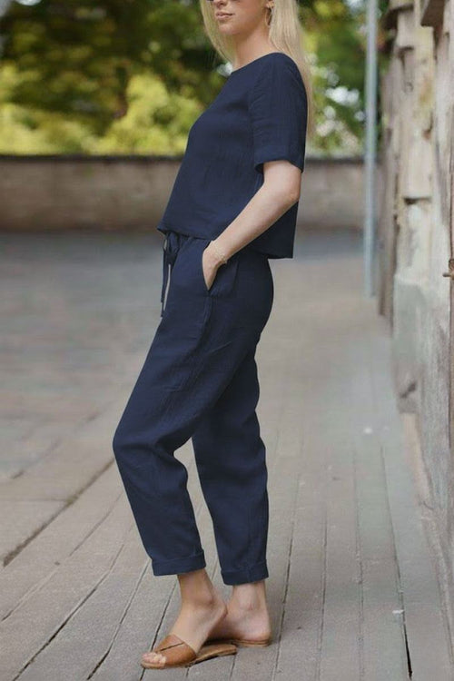 Woman wearing navy blue cotton linen set with relaxed short-sleeve top and straight-leg pants outdoors