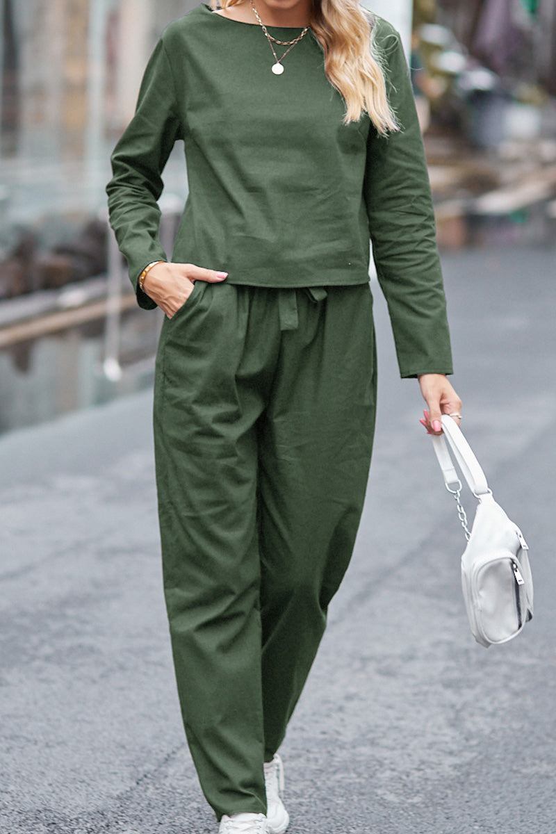Woman wearing 100% cotton linen monochrome green two-piece set with long sleeves and pants, holding white handbag outdoors