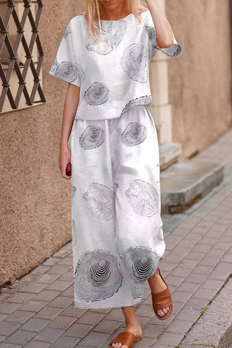 Woman wearing white loose fit co-ord set with grey circular prints and wide-leg pants walking on sidewalk