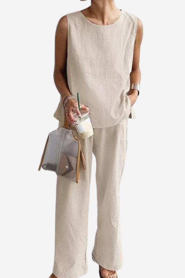 Woman wearing loose solid color sleeveless top and wide-leg pants two-piece set holding drink and transparent bag