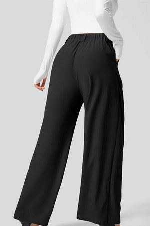 Black high-waisted plicated wide leg waffle pants with partial elastic waistband and pockets