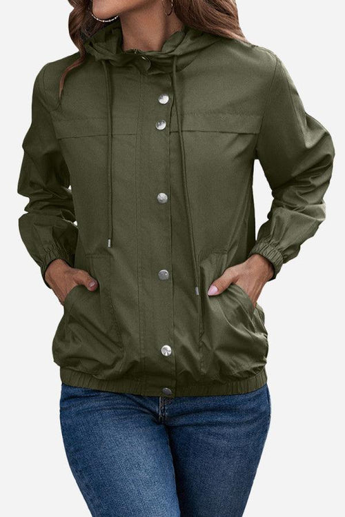 Woman wearing olive green outdoor hooded raincoat with button closure and elastic cuffs