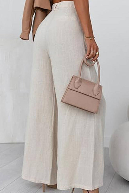 Wide leg high waist cream trousers with elastic waistband and pockets, styled with a beige handbag.