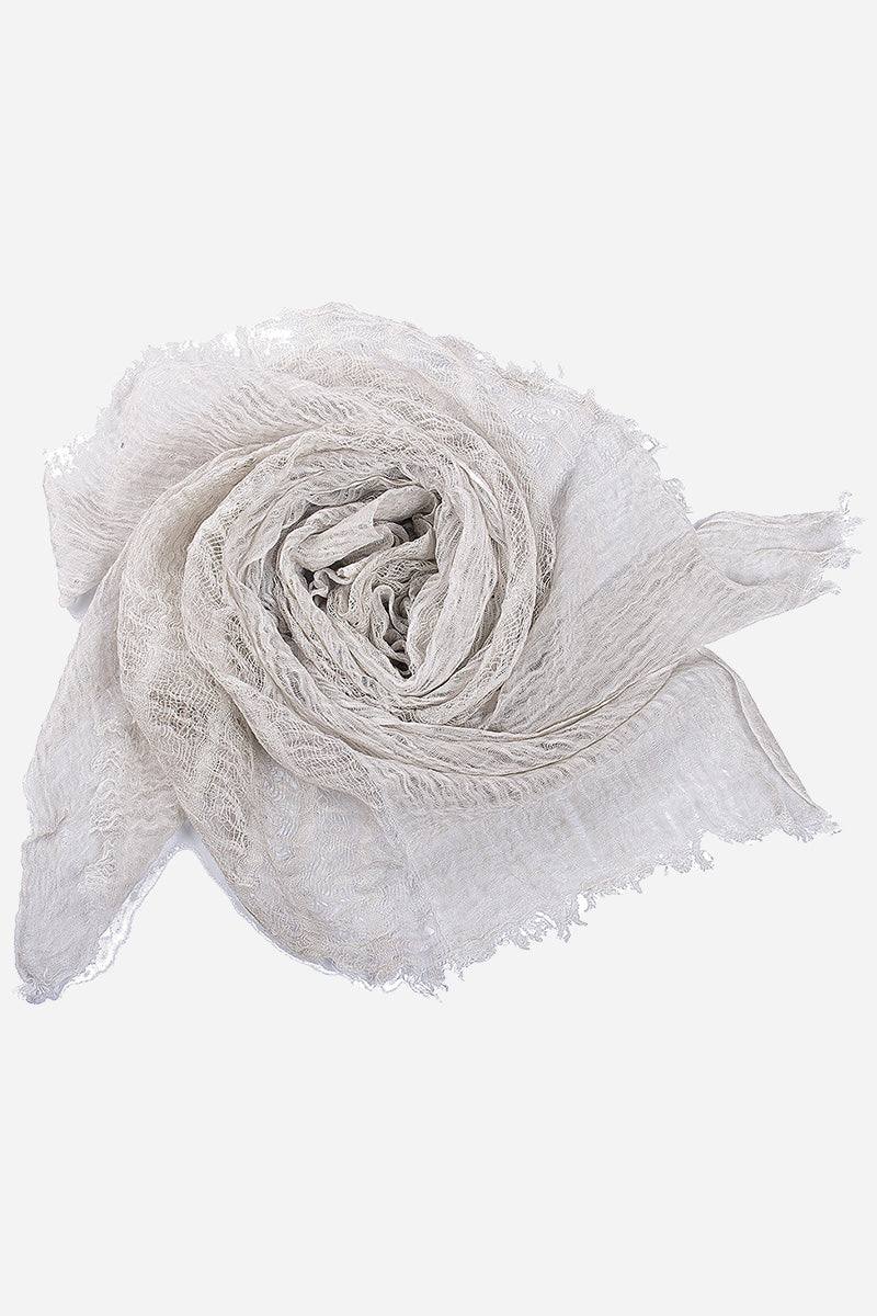 Soft lightweight linen scarf with frayed edges in a natural white color rolled up.
