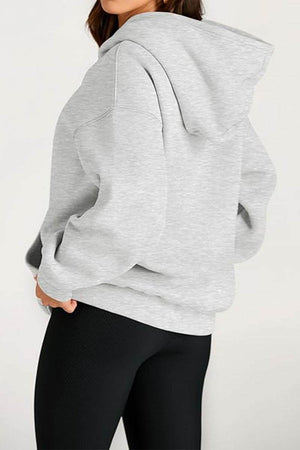 woman wearing gray oversized fleece-lined hoodie with hood and black leggings back view