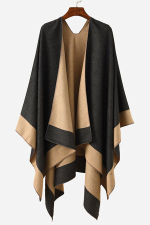 Two-tone elegant knitted poncho draped on hanger in black and beige colors