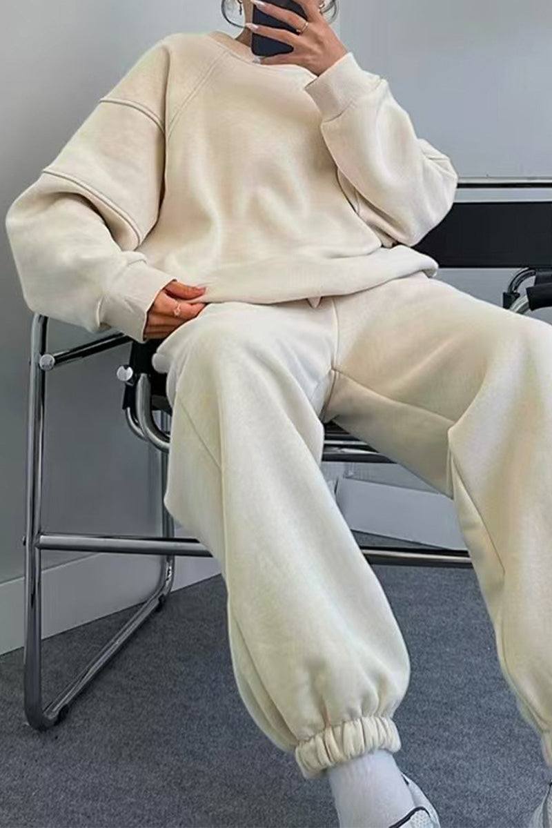 Woman wearing beige comfy chic tracksuit with relaxed fit sitting on chair