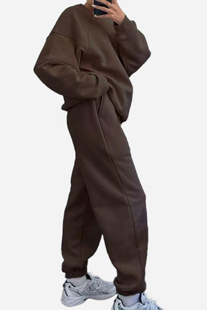 Brown comfy chic tracksuit with relaxed fit, cozy polyester fabric, and roomy pockets paired with white sneakers.