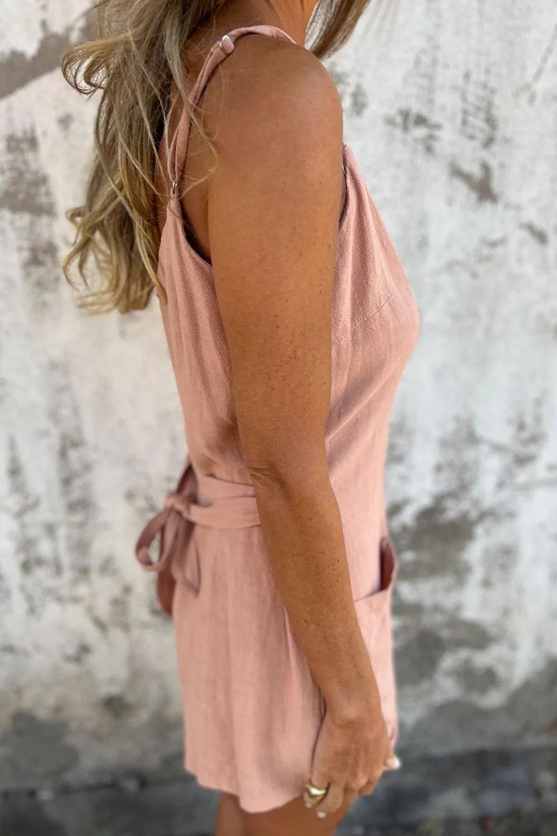 Woman wearing pink 100% pure linen breathable jumpsuit with adjustable waist tie and pockets, side view