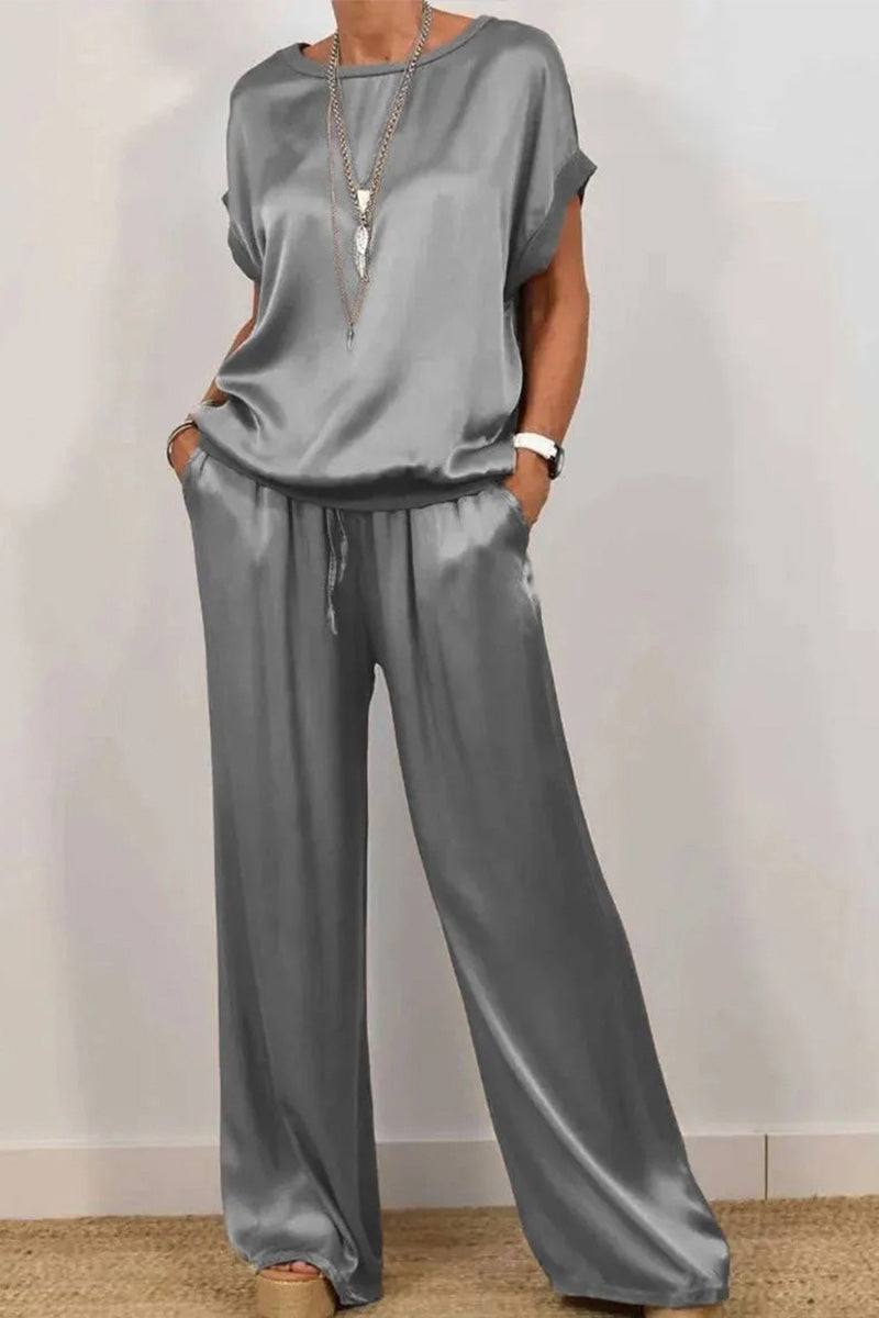 Woman wearing gray Silken Escape satin two-piece set with short sleeves and wide-leg pants with pockets