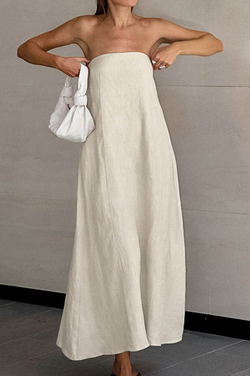 Woman wearing beige strapless A-line dress made of cotton linen blend fabric, holding a white handbag.