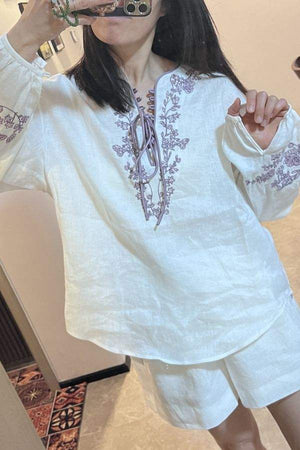 Woman wearing 100% linen two-piece set with floral embroidery in white breathable fabric