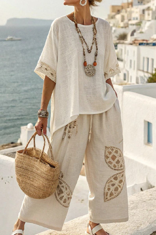 Woman wearing Coastal Comfort Linen two-piece set with crochet details, holding woven bag by seaside terrace