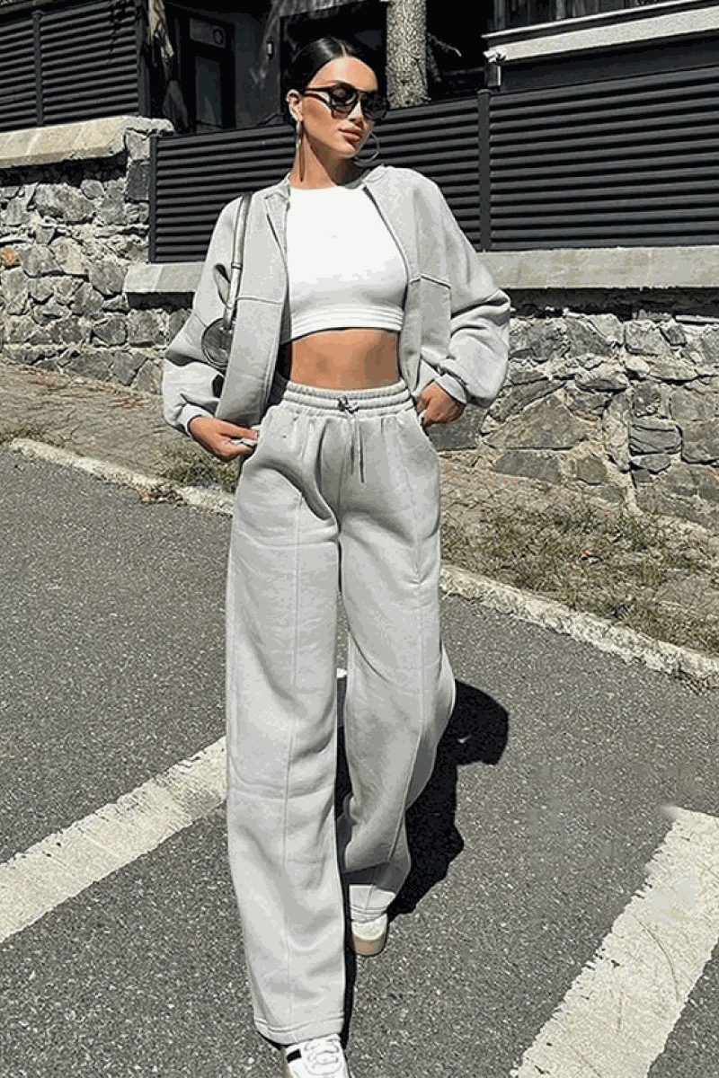 Woman wearing The Voyager Zip Set light gray zip-front sweatshirt and wide-leg joggers with pockets outdoors