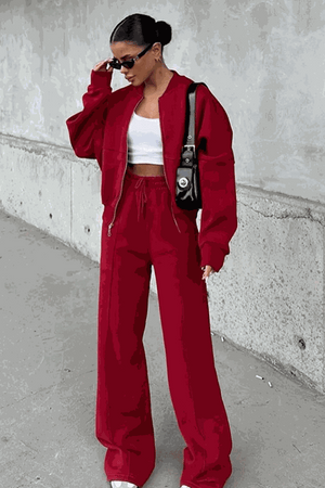 Woman wearing The Voyager Zip Set in red, featuring a relaxed zip-front sweatshirt and wide-leg joggers with pockets.
