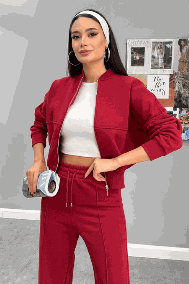 Woman wearing The Voyager Zip Set in red, featuring a zip-front sweatshirt and wide-leg joggers with pockets, styled with a white crop top and headband.