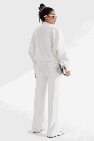 Woman wearing white Voyager Zip Set with zip-front sweatshirt and wide-leg joggers, styled with sunglasses and hair scarf, standing against white background