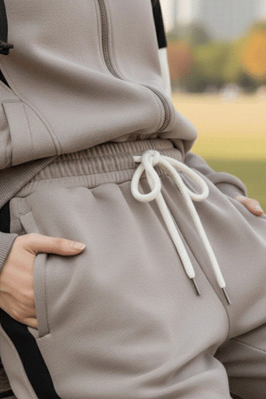Close-up of beige Comfort in Motion athleisure tracksuit with drawstring waist and hands in pockets