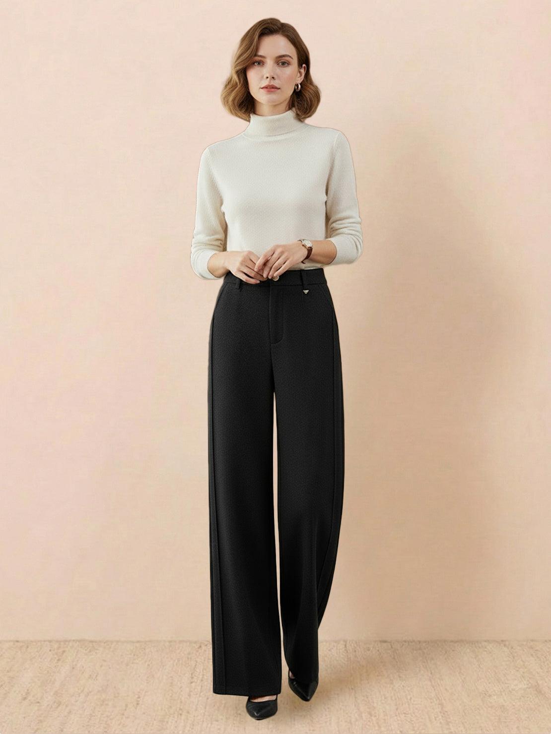 Black thermal wool blend trousers with wide-leg silhouette modeled by woman in white turtleneck sweater against beige background