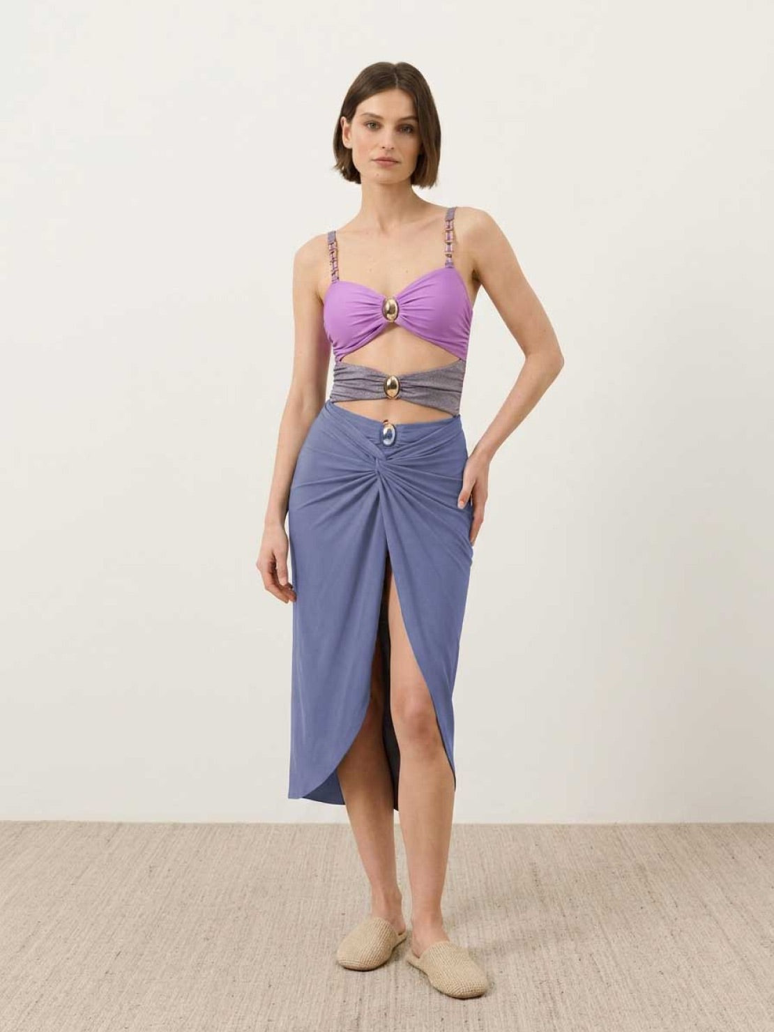 Gold-detail cutout one-piece swimsuit with ruched panels and gold dome accent, paired with midi wrap skirt beach cover-up