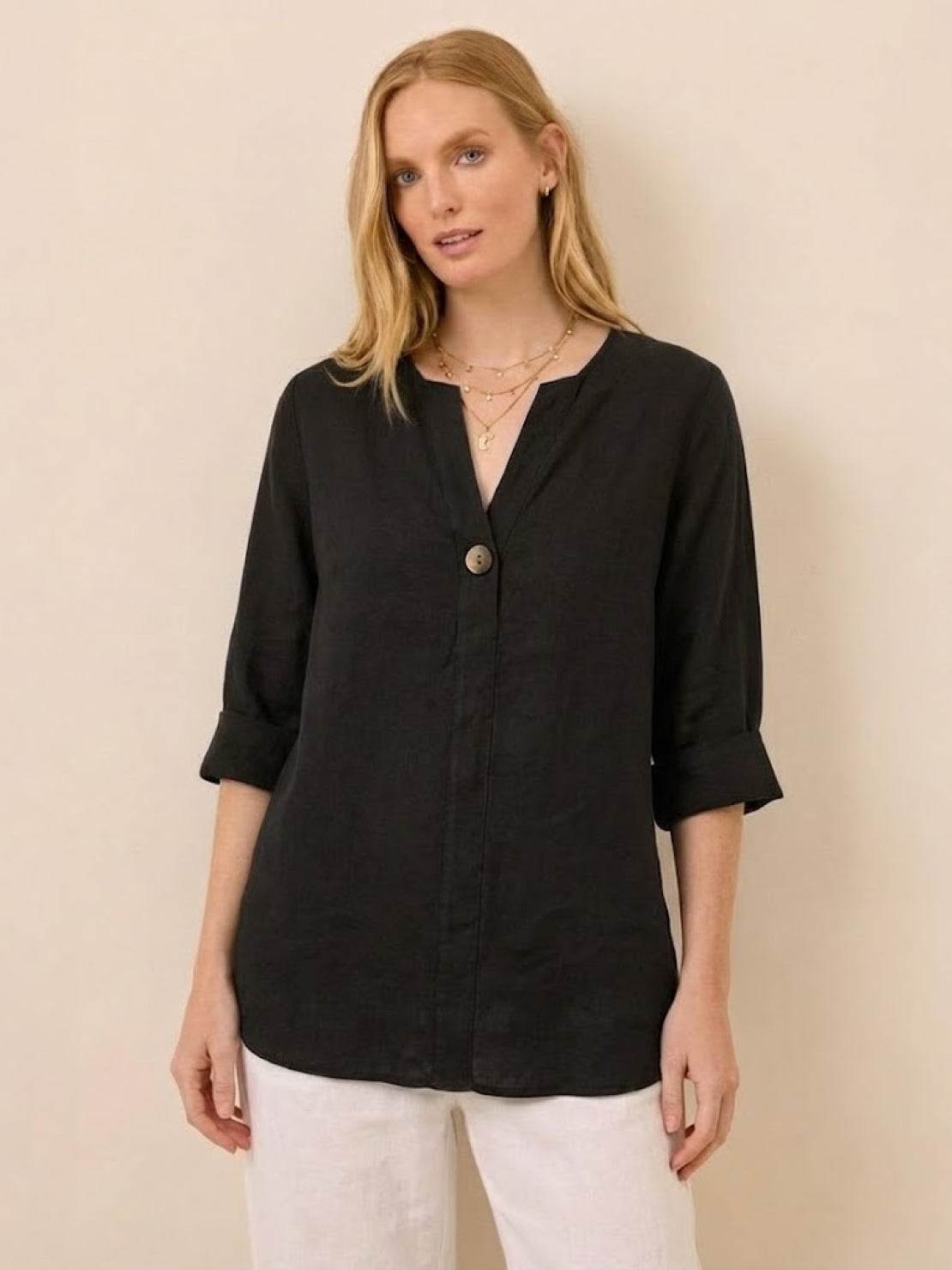 Woman wearing a black pure linen age-defying shirt with button detail and rolled-up sleeves