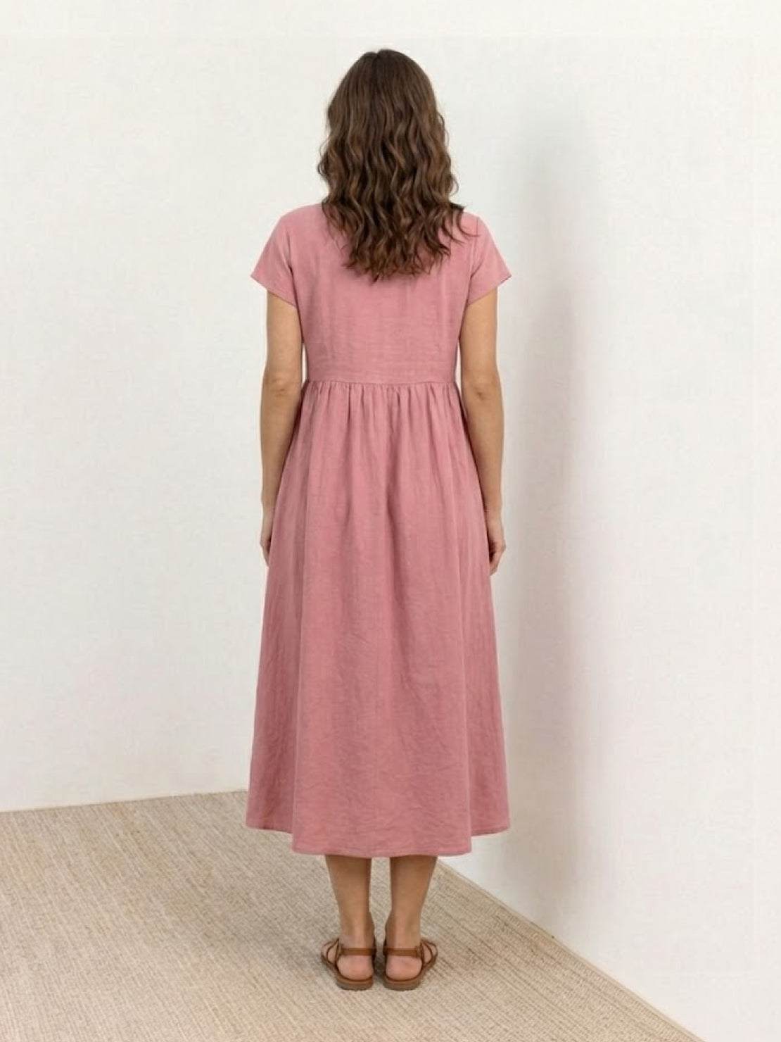 Woman modeling capped-sleeve voluminous pleated midi dress with flowing skirt and pockets