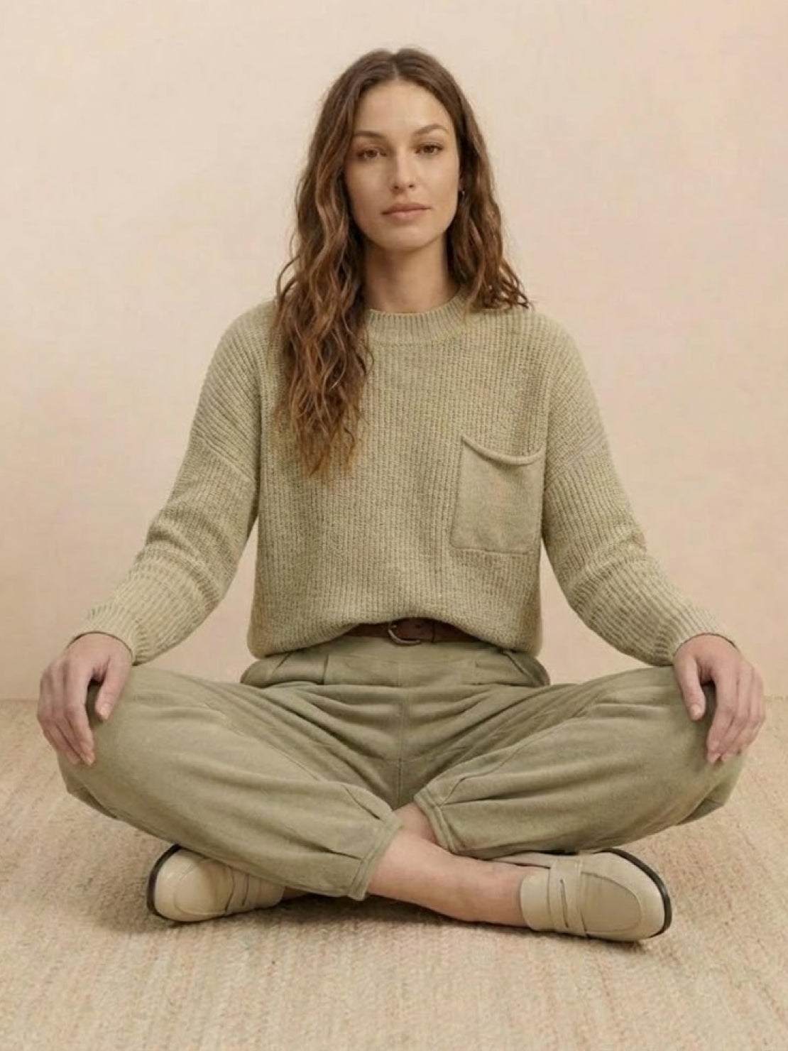 Woman wearing European minimalism relaxed khaki knit sweater and trouser set sitting cross-legged