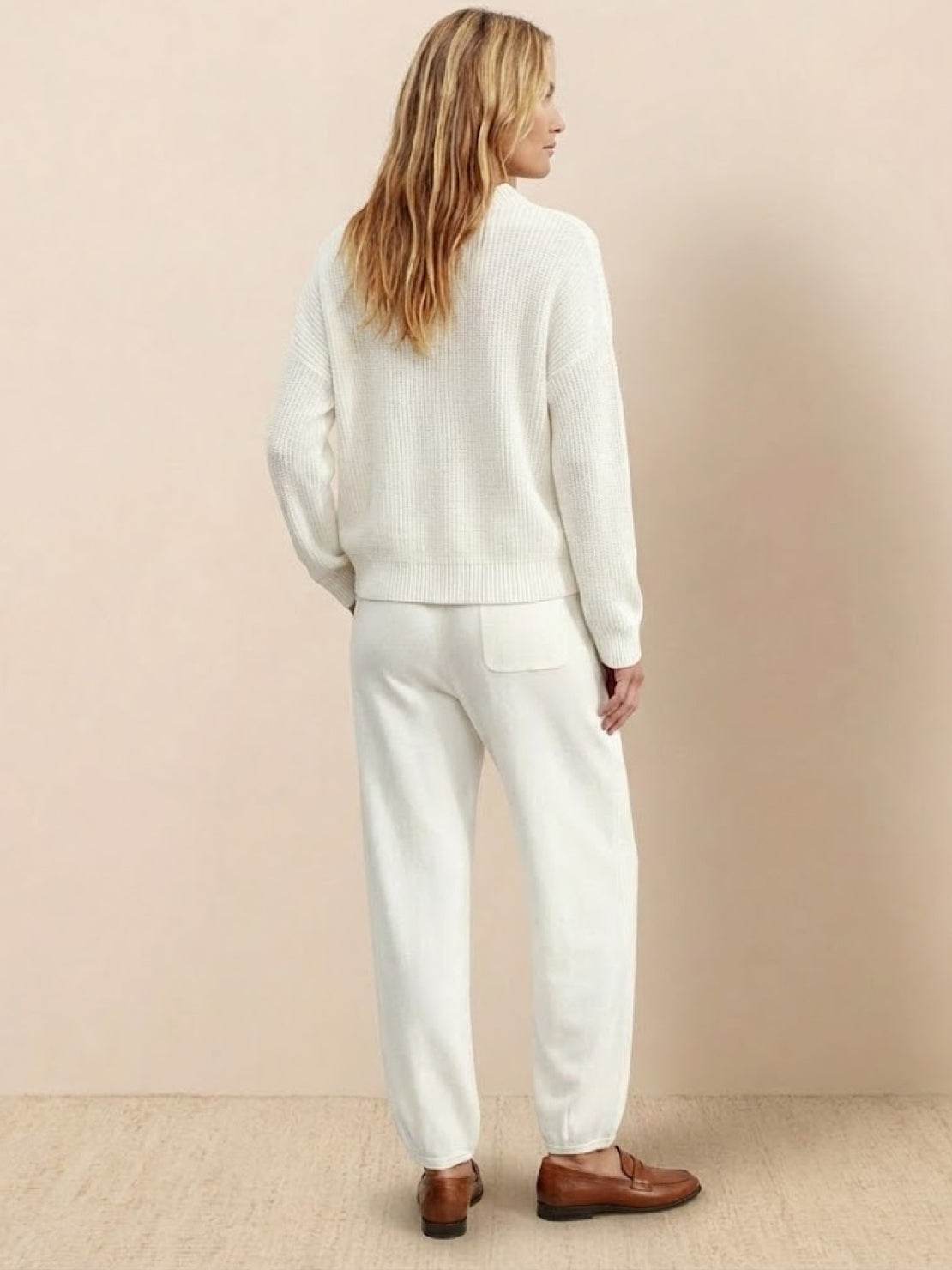 Woman wearing white relaxed knit sweater top and trousers set in European minimalism style