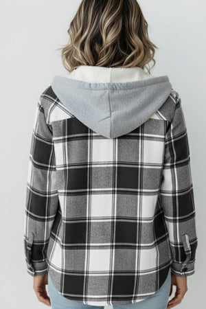 Back view of a woman wearing a black and white Highland Plaid Shacket with a grey hood and fleece lining.