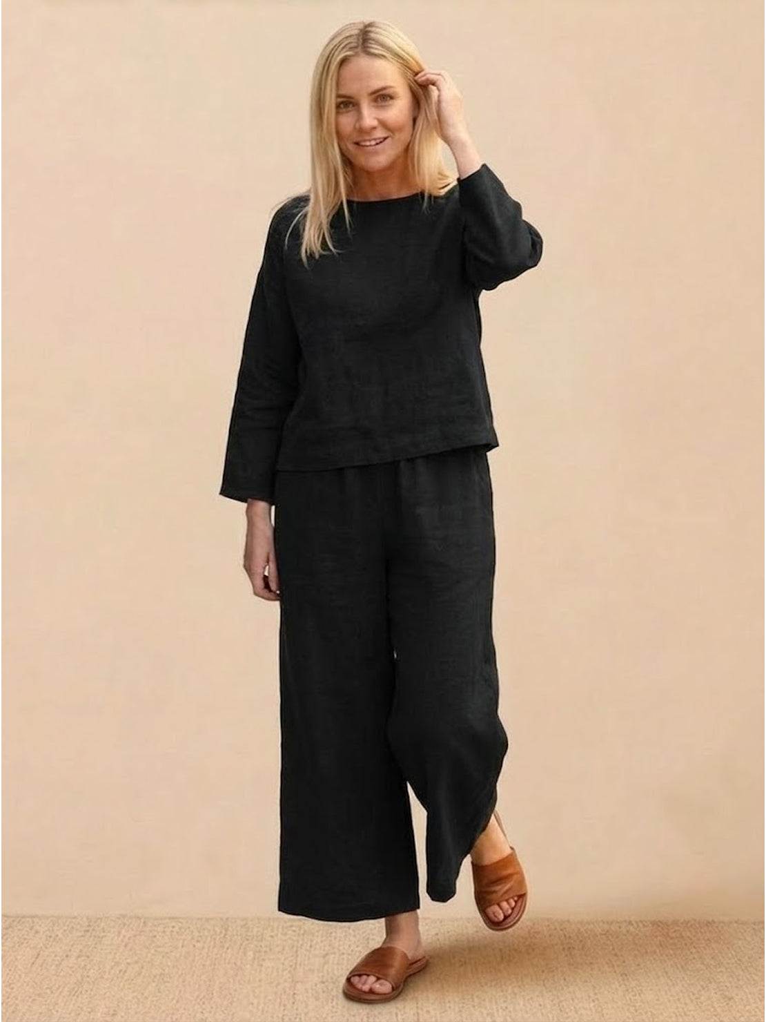 Woman wearing loose solid color two-piece set with wide-leg pants and pullover top in neutral tones