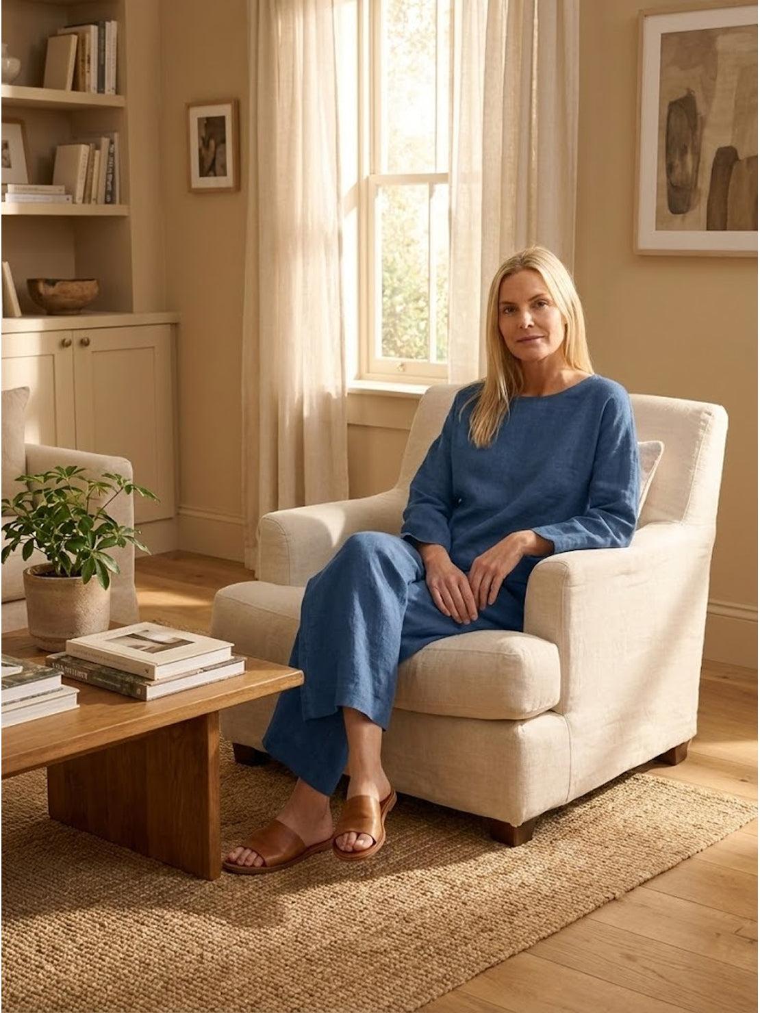 woman wearing loose solid color two-piece set sitting in beige armchair in cozy living room