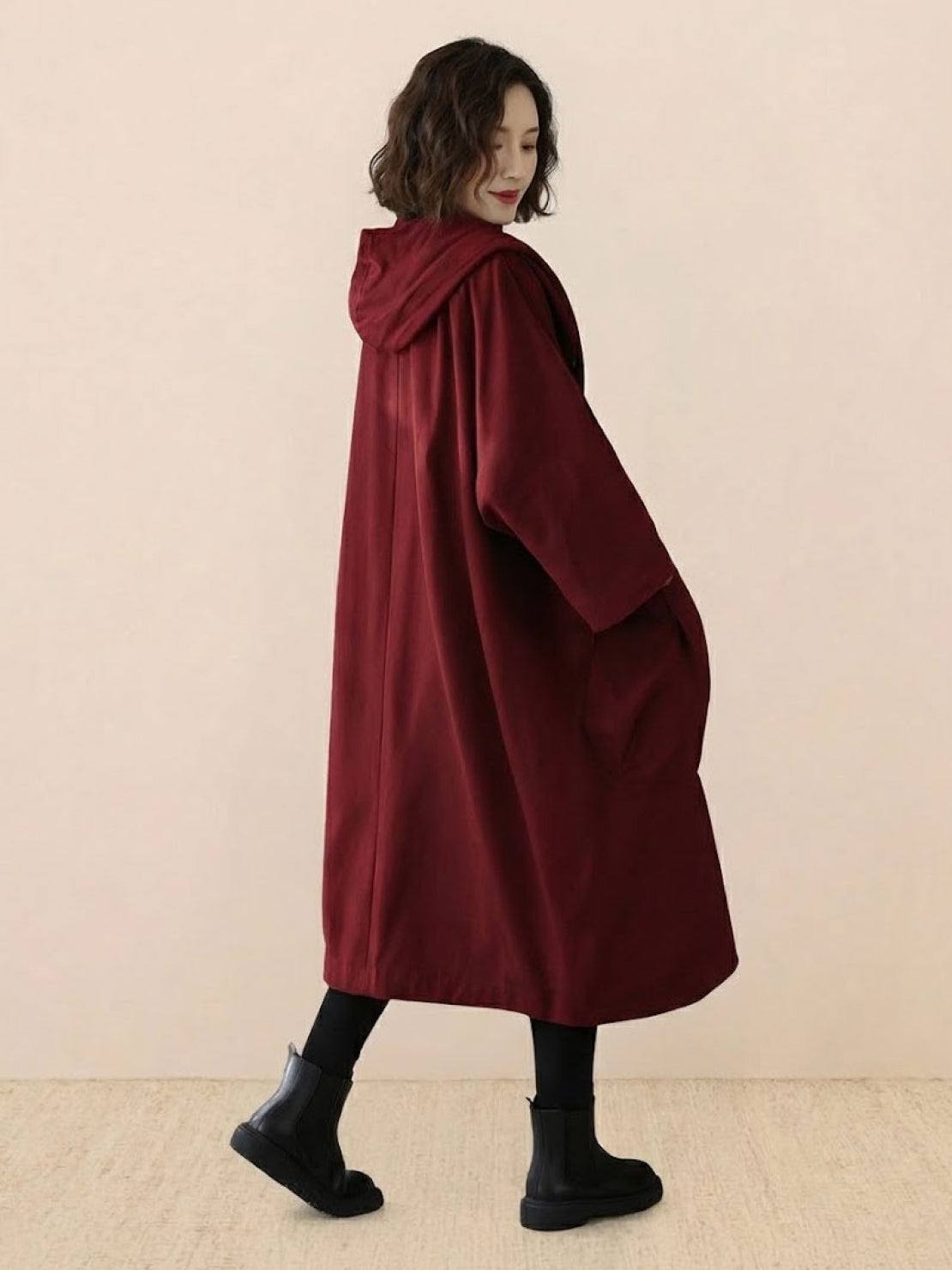Woman wearing oversized waterproof design maroon windbreaker jacket with hood and longline fit