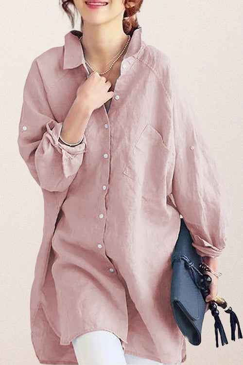 Woman wearing oversized pink linen shirt holding blue clutch bag