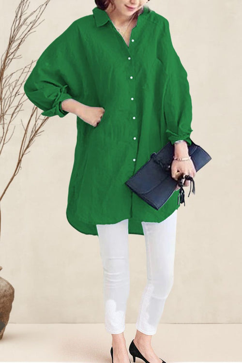 Woman wearing oversized green linen shirt with white pants and black heels, holding a black clutch bag