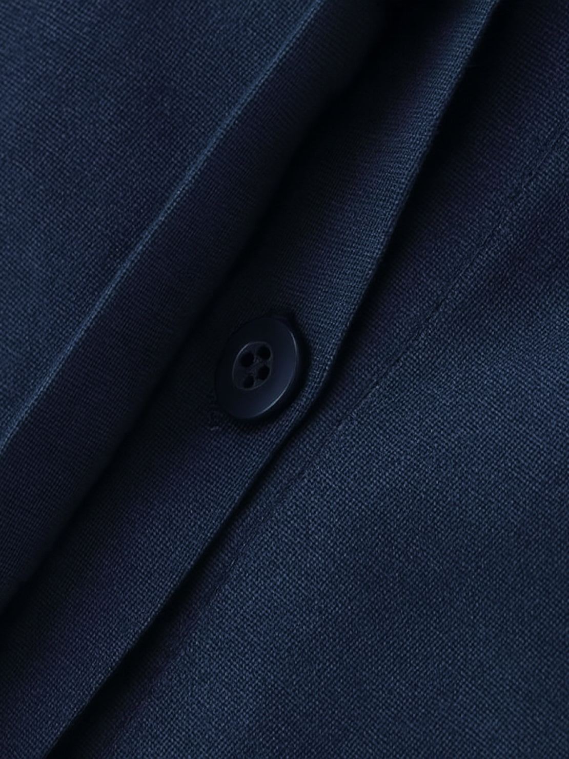 Close-up of oversized 100% cotton navy blue shirt fabric with button detail