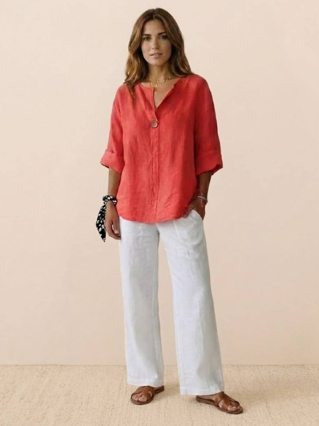 Woman wearing coral pure linen age-defying shirt with button detail and white linen pants
