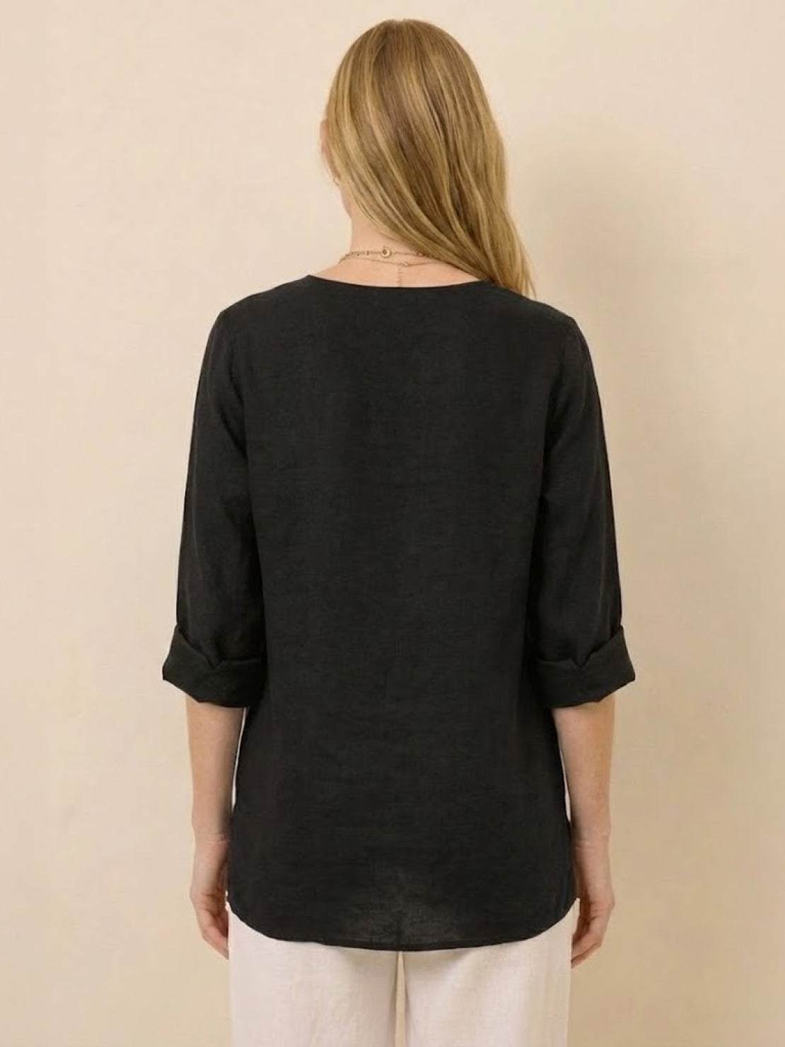 Back view of woman wearing black Pure Linen Age-Defying Shirt with rolled sleeves and relaxed fit.