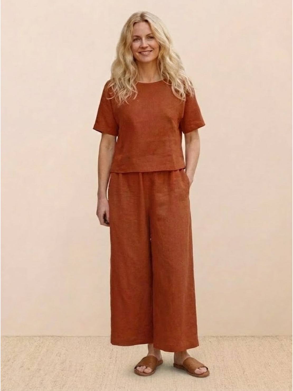 Woman wearing rust-colored loose fit co-ord set with short sleeves and wide-leg pants.