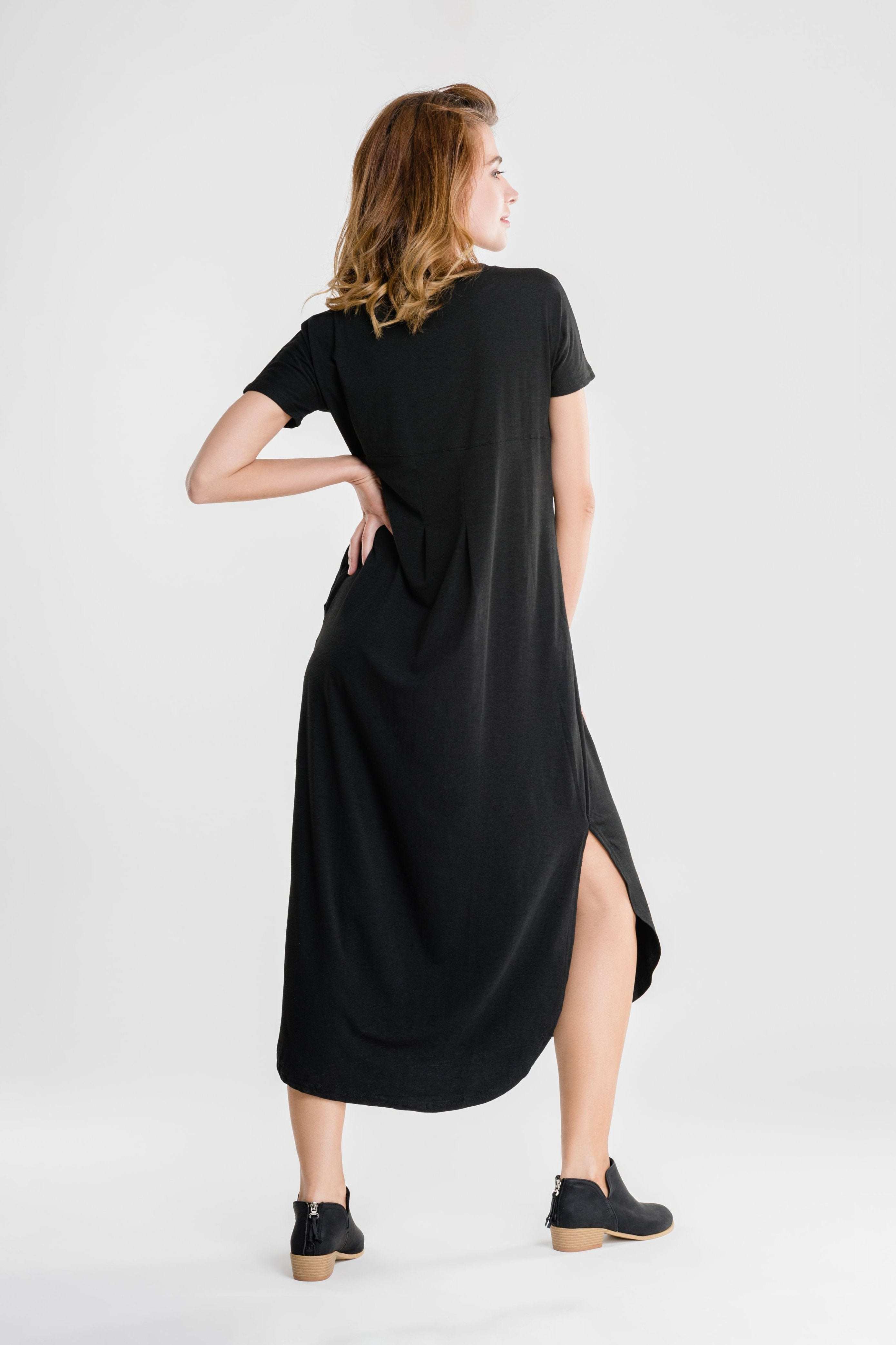 Woman wearing black side slit maxi dress with short sleeves and pockets, shown from the back