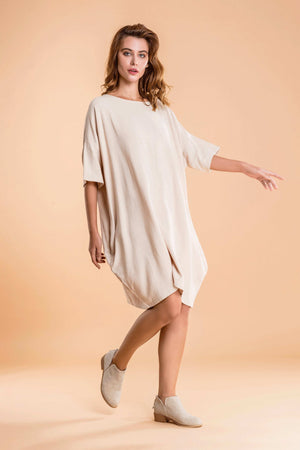 Woman wearing nude oversized premium linen ovoid dress with short sleeves and discreet pockets