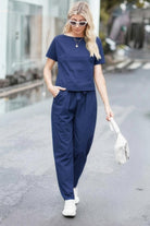 Woman wearing navy blue cotton linen set with short sleeve top and drawstring pants walking outdoors