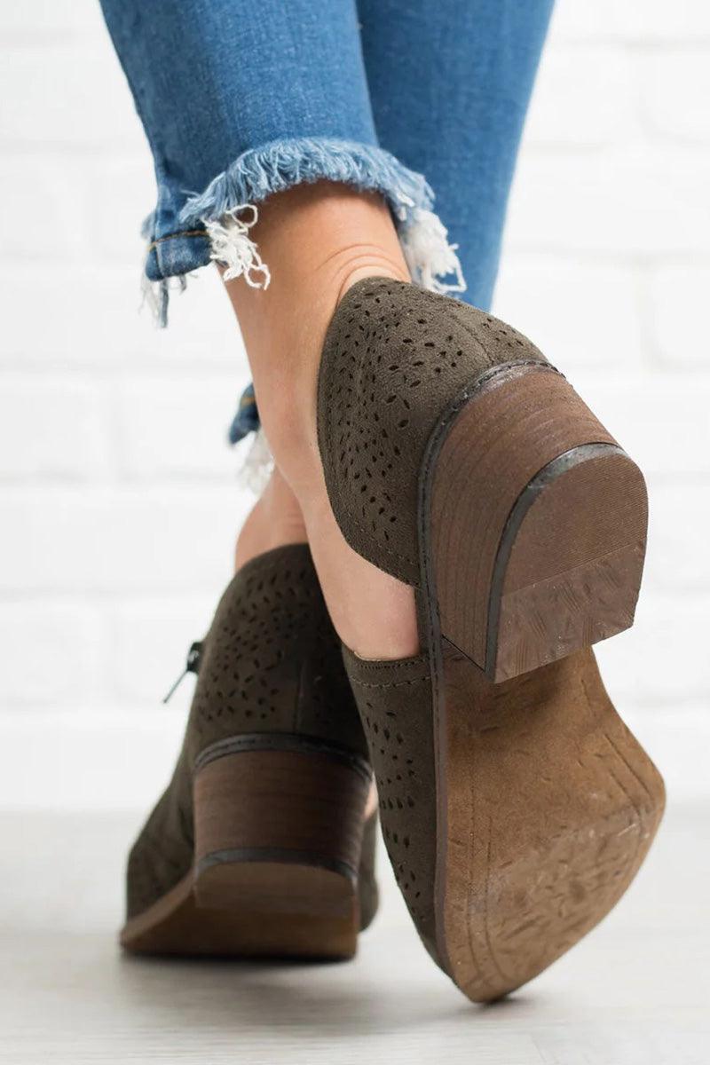 Close-up of laser cut western ankle boots with low heels and zipper detail, worn with frayed hem jeans