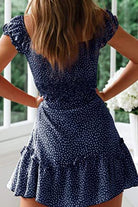 Back view of woman wearing navy blue sweetheart collar printed ruffled maxi dress with short sleeves and high waist design.