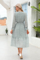 Woman wearing Bloom Wrap Midi Dress with delicate floral print, airy trumpet sleeves, and A-line silhouette walking outdoors