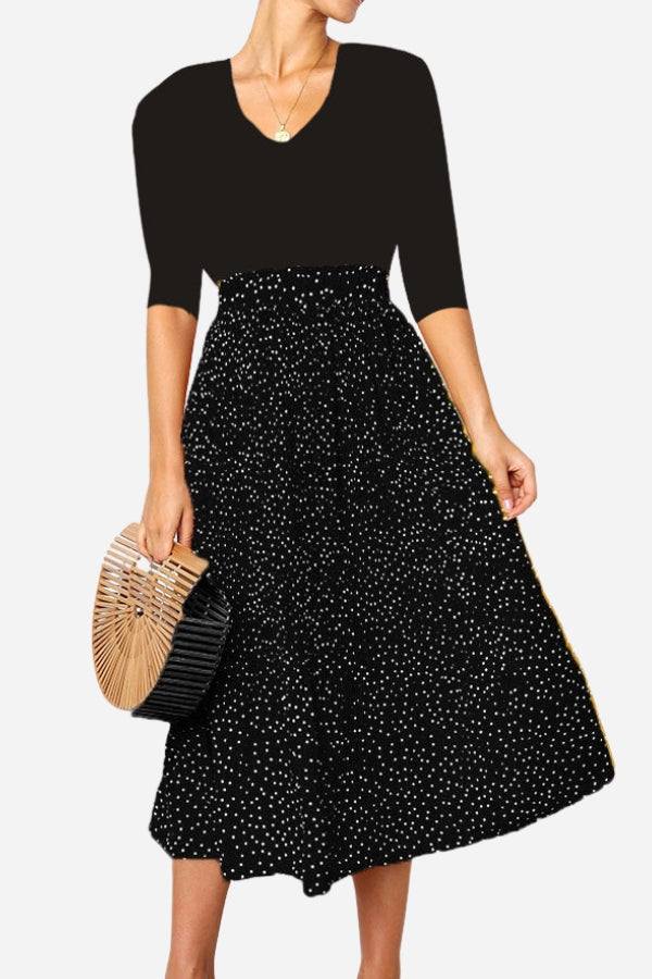 Woman wearing an effortlessly chic polka dot pleated high-waist midi skirt set with pockets and a black top holding a wooden handbag