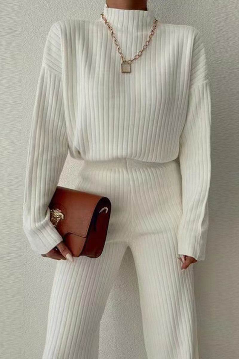 Timeless Striped Two-Piece knitwear set in soft white ribbed polyester with long sleeves and matching pants, styled with a brown handbag and gold necklace.