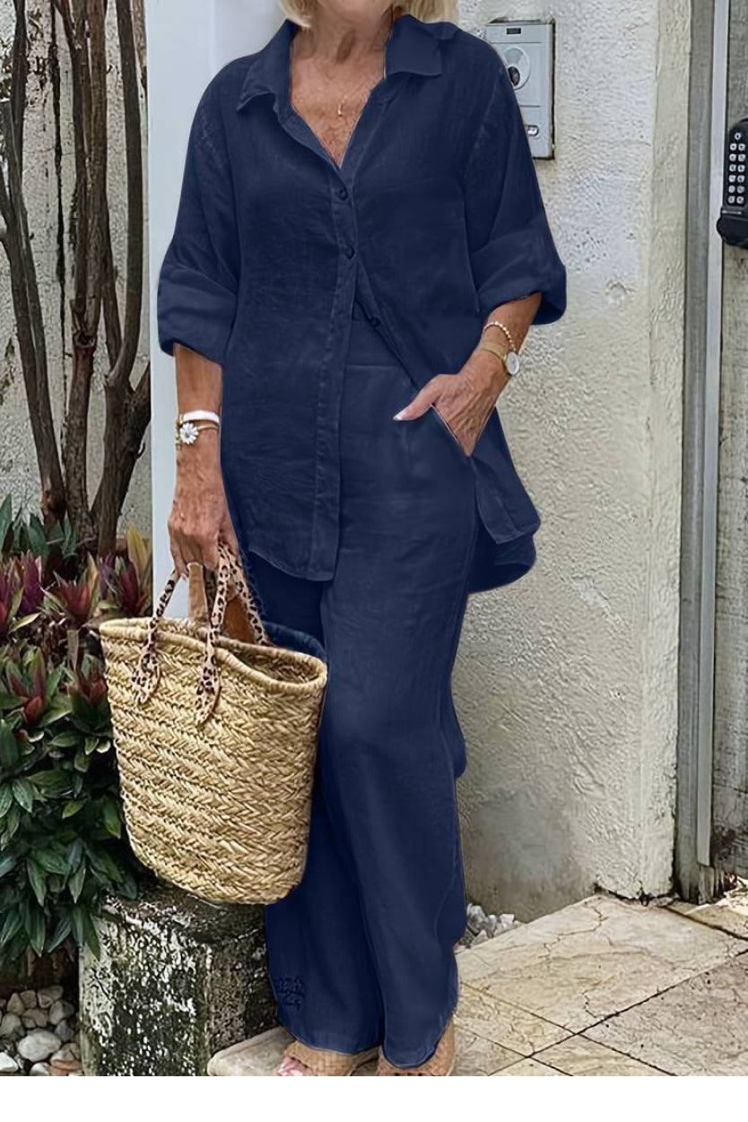 Woman wearing navy relaxed shirt and trousers two-piece set holding woven handbag outdoors