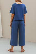 Rear view of model wearing blue loose fit co-ord set with wide-leg trousers and short sleeve top