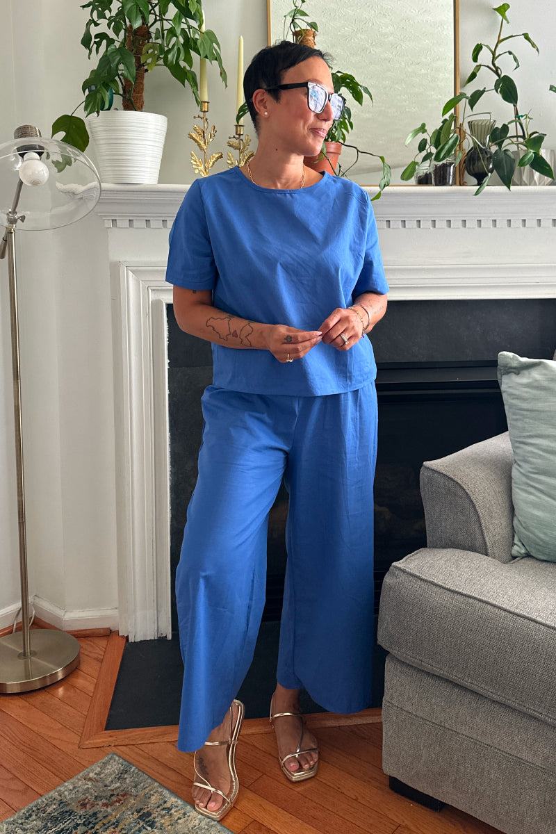 Woman wearing a blue loose fit co-ord set with short sleeves and wide-leg pants in a cozy living room.